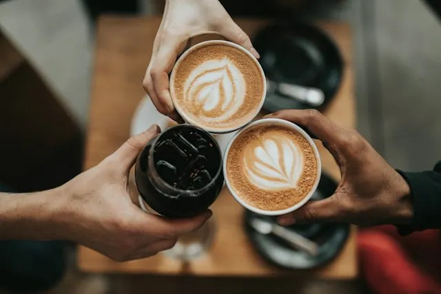 Latte fincanlarıyla tokuşturan üç el